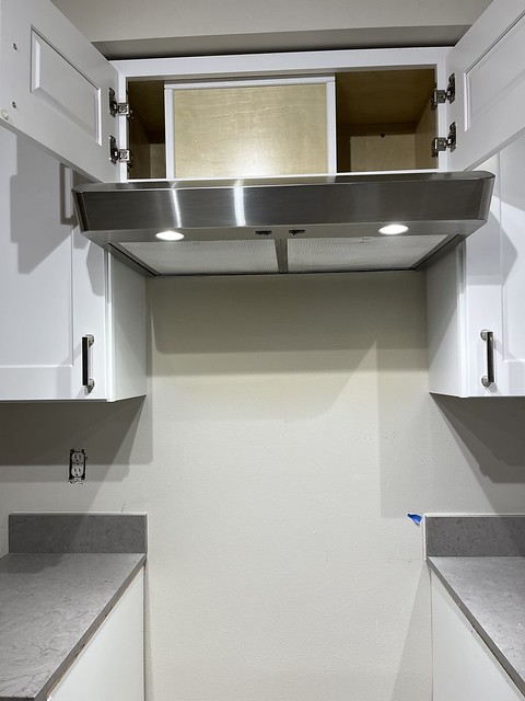 Finished hood vent installation between new white cabinets