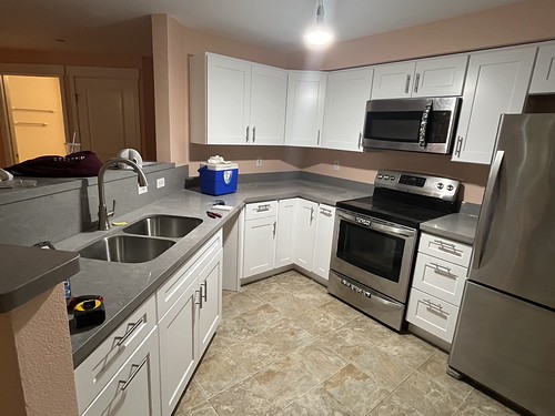 Newly installed kitchen cabinets white with chrome cabinet pulls and countertop new