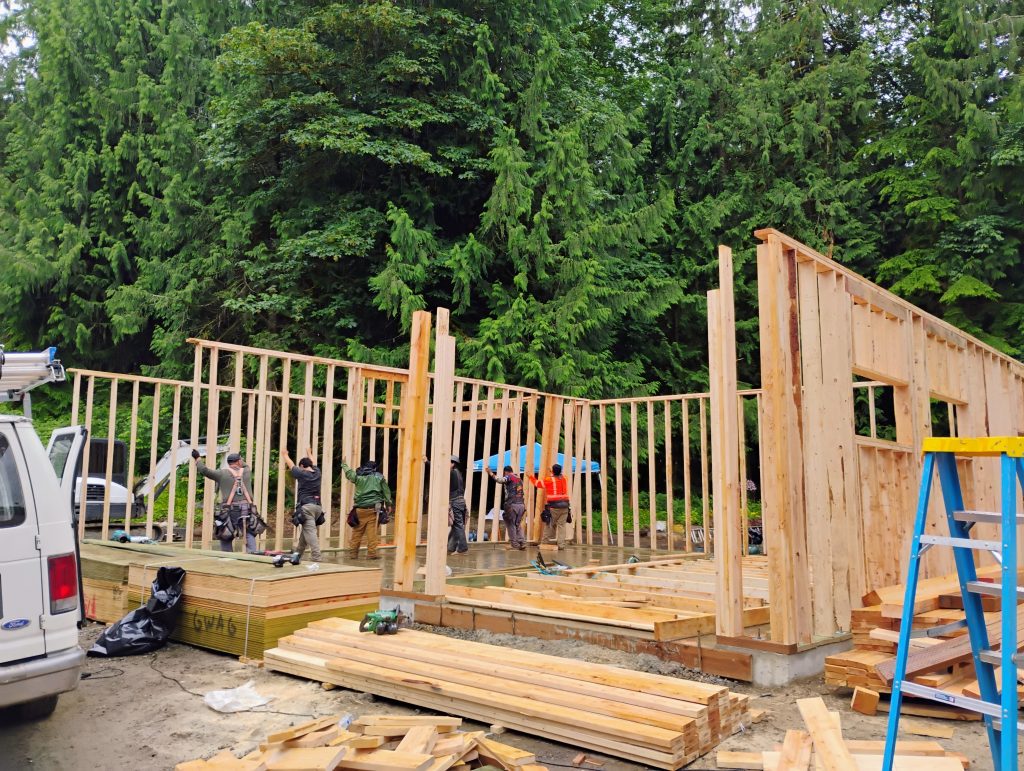 Framing Crew Lifting up a Framed Wall While Constructing a Building